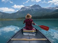 woman in canoe on lake with outlook of mountains